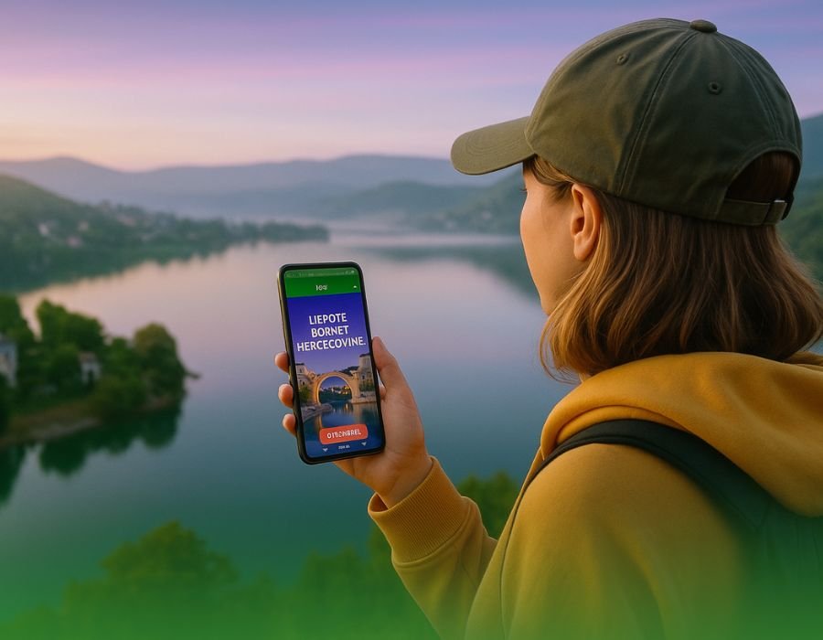 Turistkinja gleda panoramu Plivskog jezera u Bosni i Hercegovini, držeći telefon s otvorenom LoveBiH aplikacijom, s blagim nijansama brend-boja na nebu